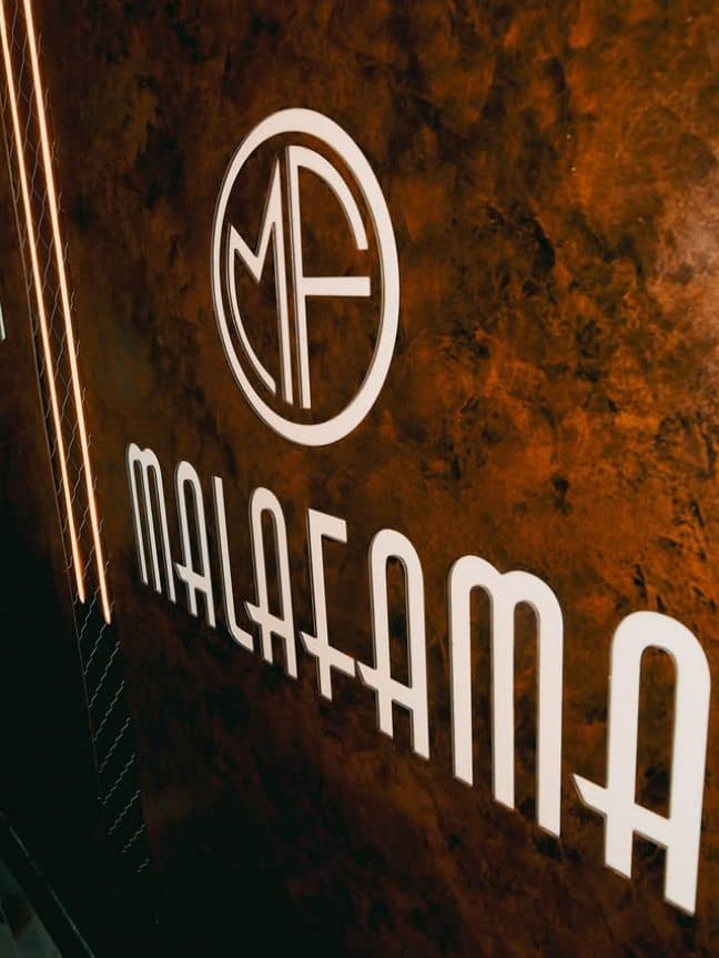 Logotipo de MALAFAMA en relieve sobre la pared de óxido del club