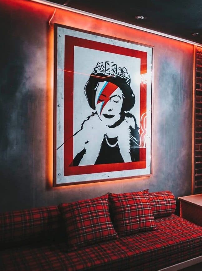 Reservado con sofá de tartán rojo bajo un cuadro retroiluminado en neón